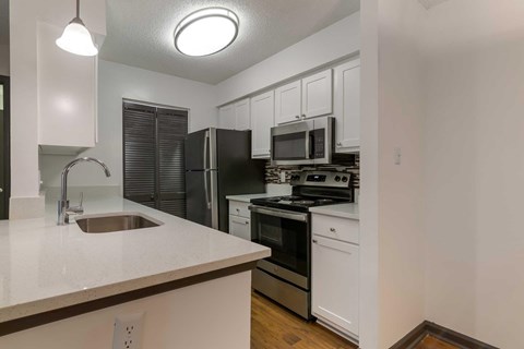 A kitchen with white cabinets and black appliances.