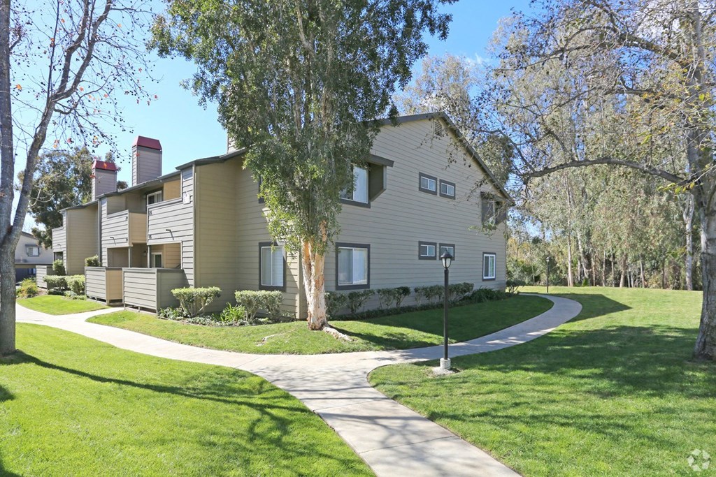 a house with a sidewalk and trees in front of it
