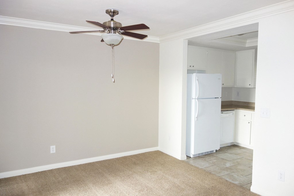 a bedroom with a ceiling fan and a kitchen in the background