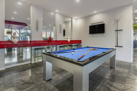 A pool table in a room with a television mounted on the wall.