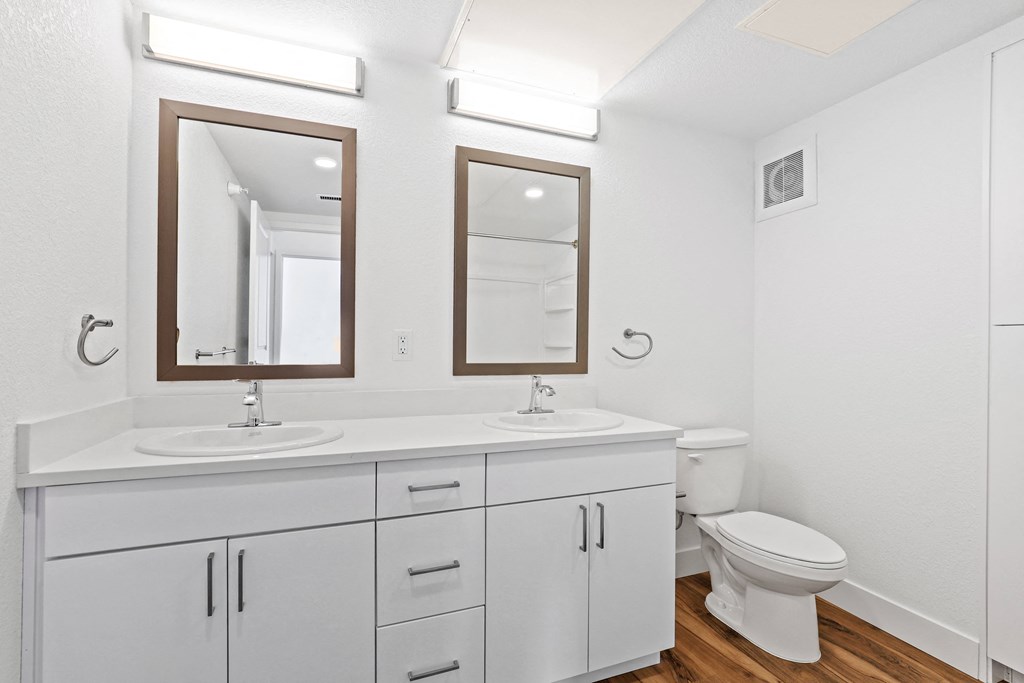 a bathroom with a sink and a toilet and two mirrors