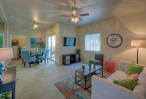 A living room with a couch, chairs, and a ceiling fan.