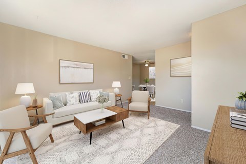 A living room with carpet, a couch, 2 chairs, a rug, and a coffee table.