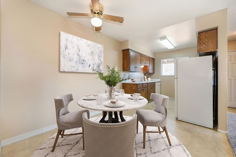 A dining room with a table set and a ceiling fan above.
