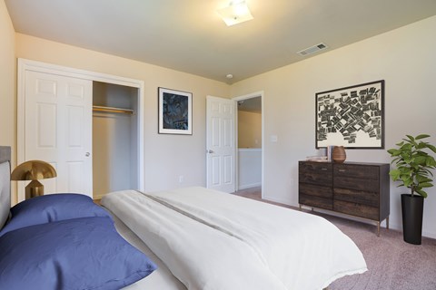 A bedroom with a bed, dresser, and a painting on the wall.