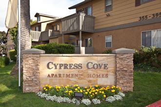 a sign for cypress cove apartments with yellow and white flowers