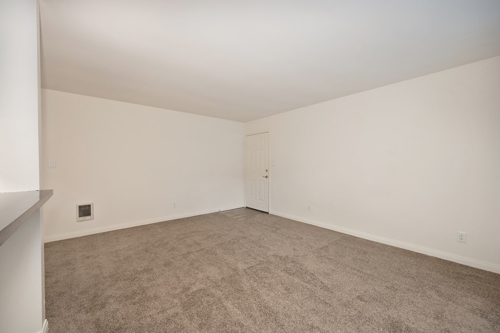 an empty living room with carpet and white walls