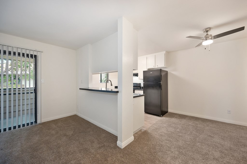 an empty living room and kitchen with a refrigerator and sink