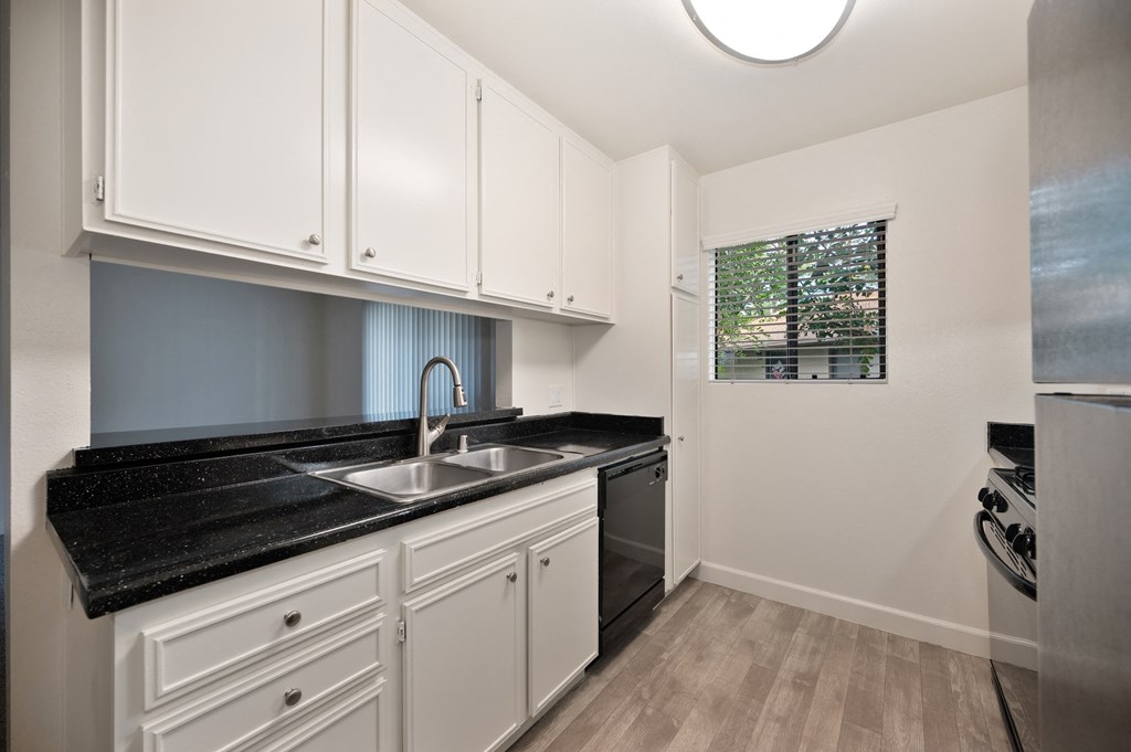 a kitchen with white cabinets and a black counter top and a sink