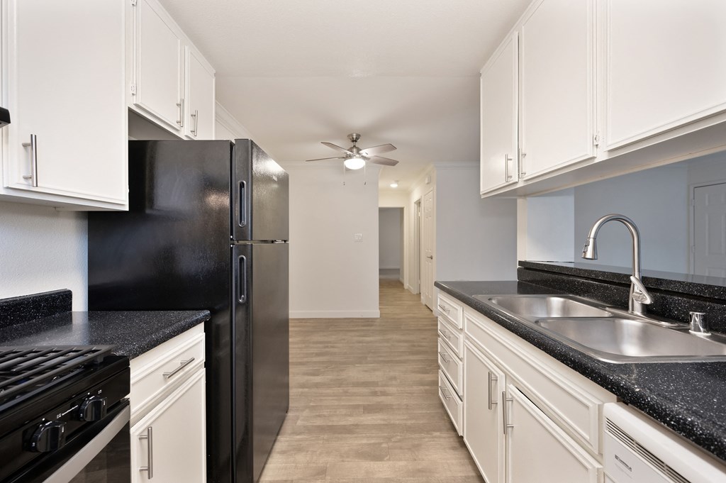 a kitchen with white cabinets and black counter tops and a black refrigerator