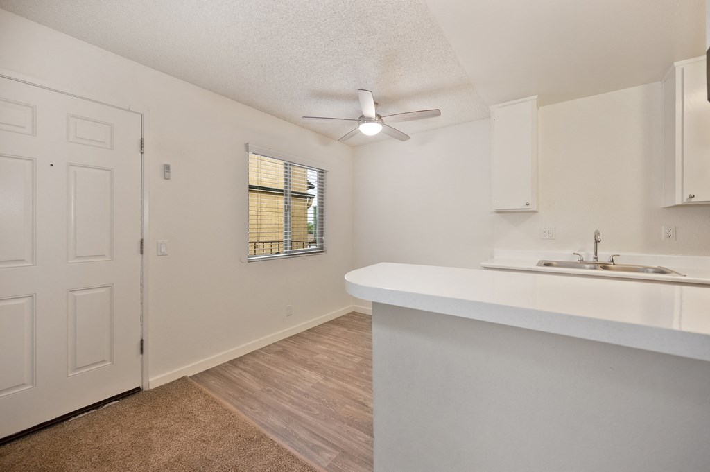 an open kitchen and living room with a white counter top and a door to a