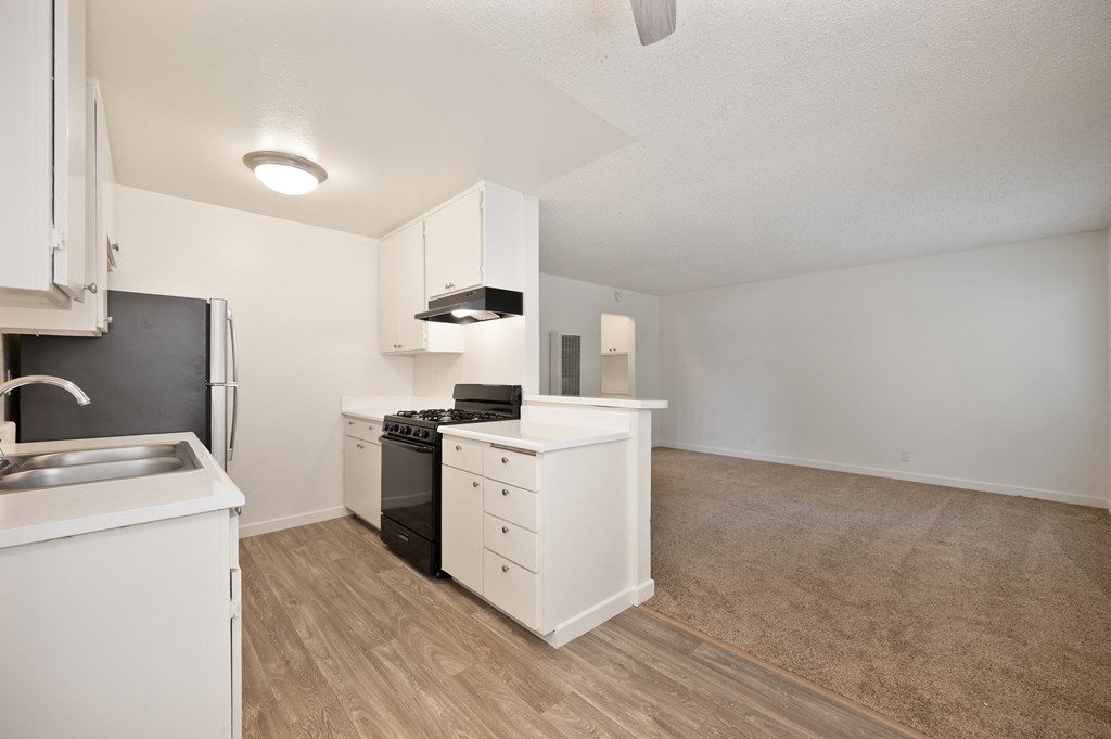 an empty kitchen with white cabinets and a black stove and refrigerator