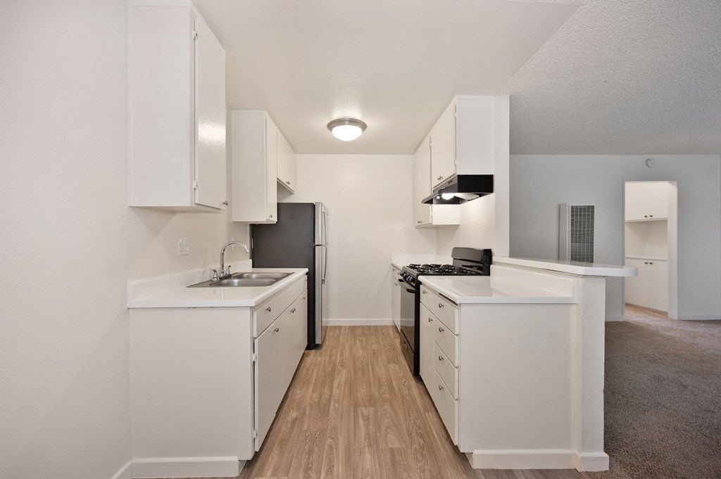 a spacious kitchen with white cabinets and appliances and a black refrigerator