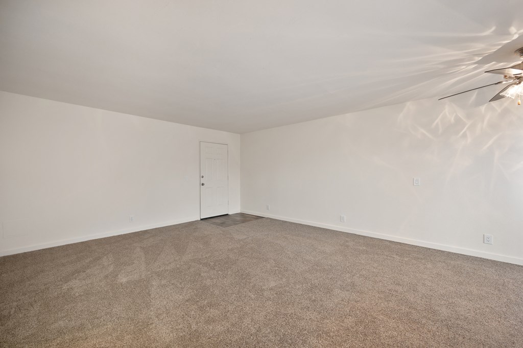 an empty living room with carpet and white walls
