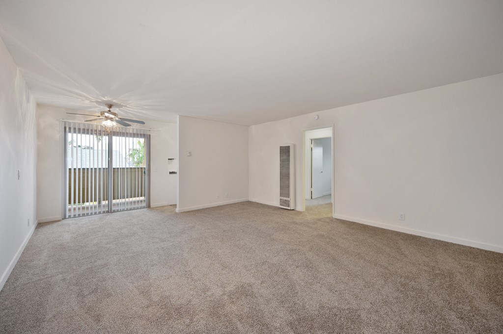 an empty living room with a ceiling fan and a window