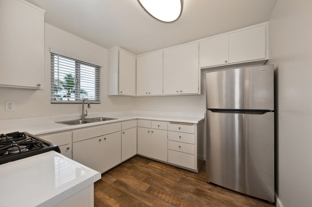 an empty kitchen with white cabinets and a stainless steel refrigerator