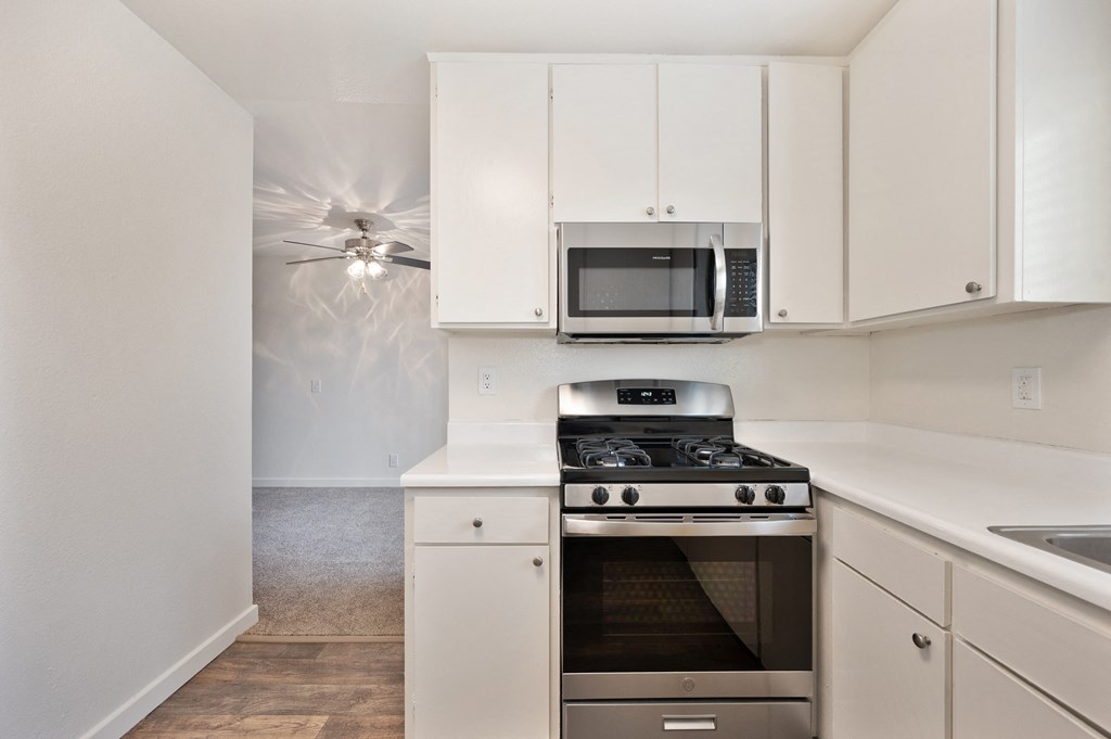 an empty kitchen with white cabinets and stainless steel appliances