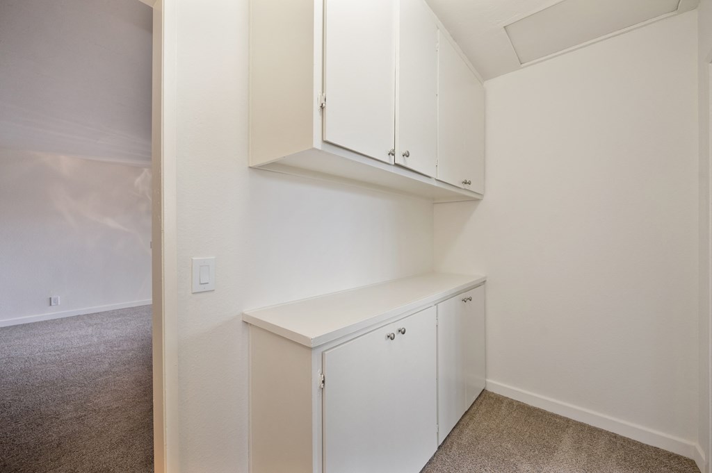 an empty room with white cabinets and white walls and carpet