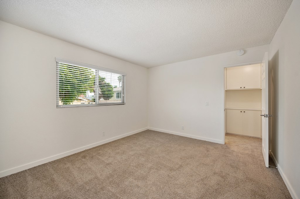 an empty living room with a window and a closet