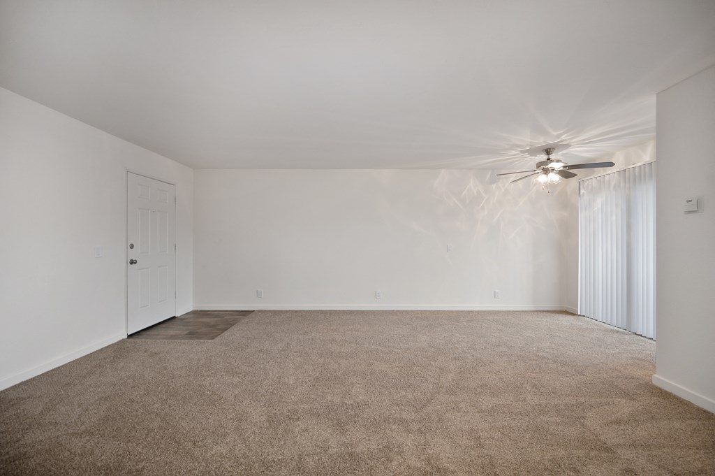 an empty living room with carpet and a ceiling fan