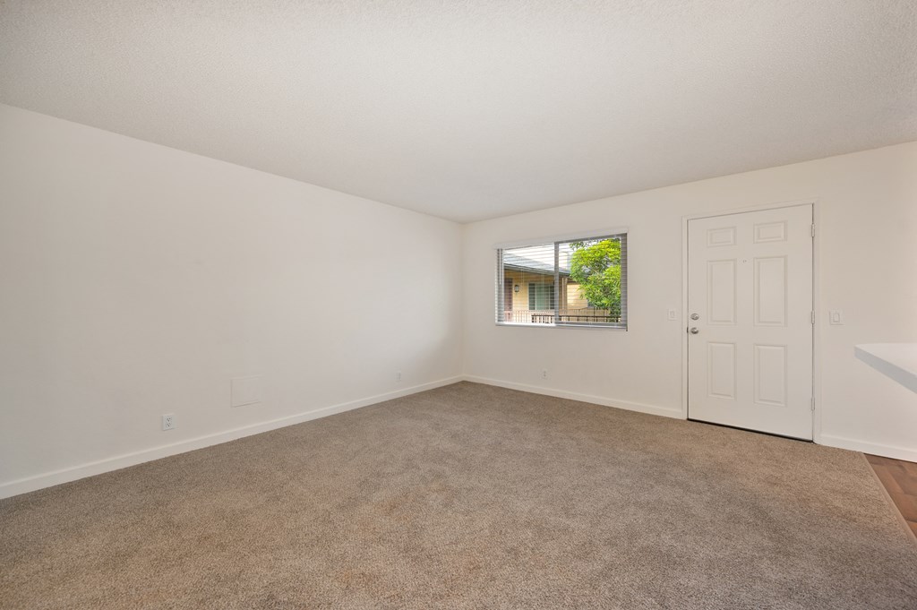 an empty living room with carpet and a door to a balcony