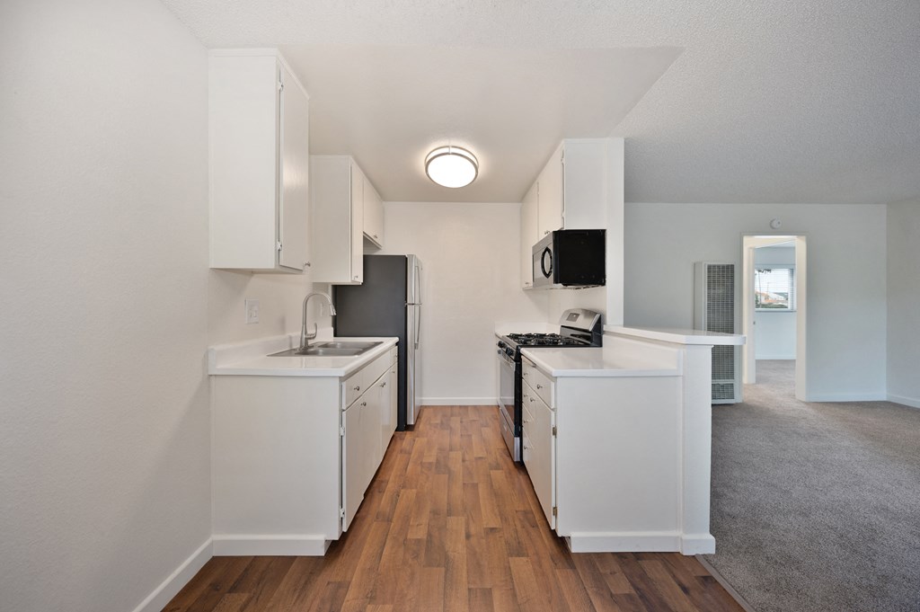 an empty kitchen with white cabinets and a black refrigerator and stove