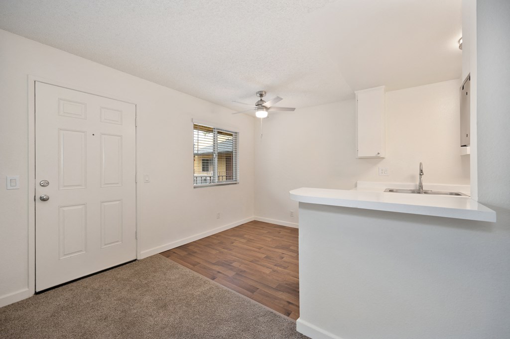an empty living room and kitchen with a sink and a door