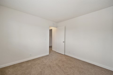 a bedroom with white walls and carpet.