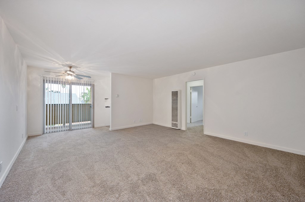 an empty living room with a window and a ceiling fan