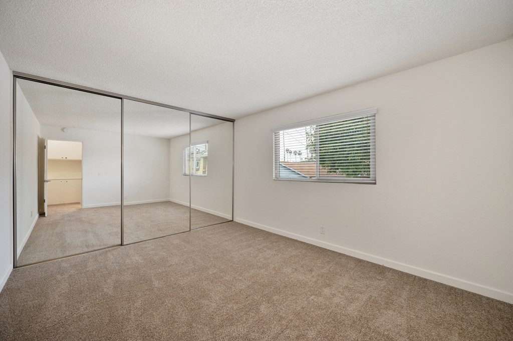 an empty living room with mirrored walls and a large window