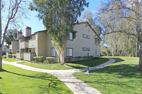 The exterior of the community with a walkway, grass, and trees.