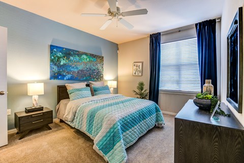 Model apartment bedroom with a bed, nightstand, and a painting on the wall.