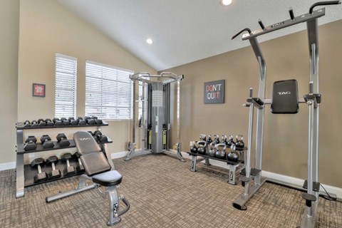 A gym with a bench, weights, and a sign that says "Don't Quit".