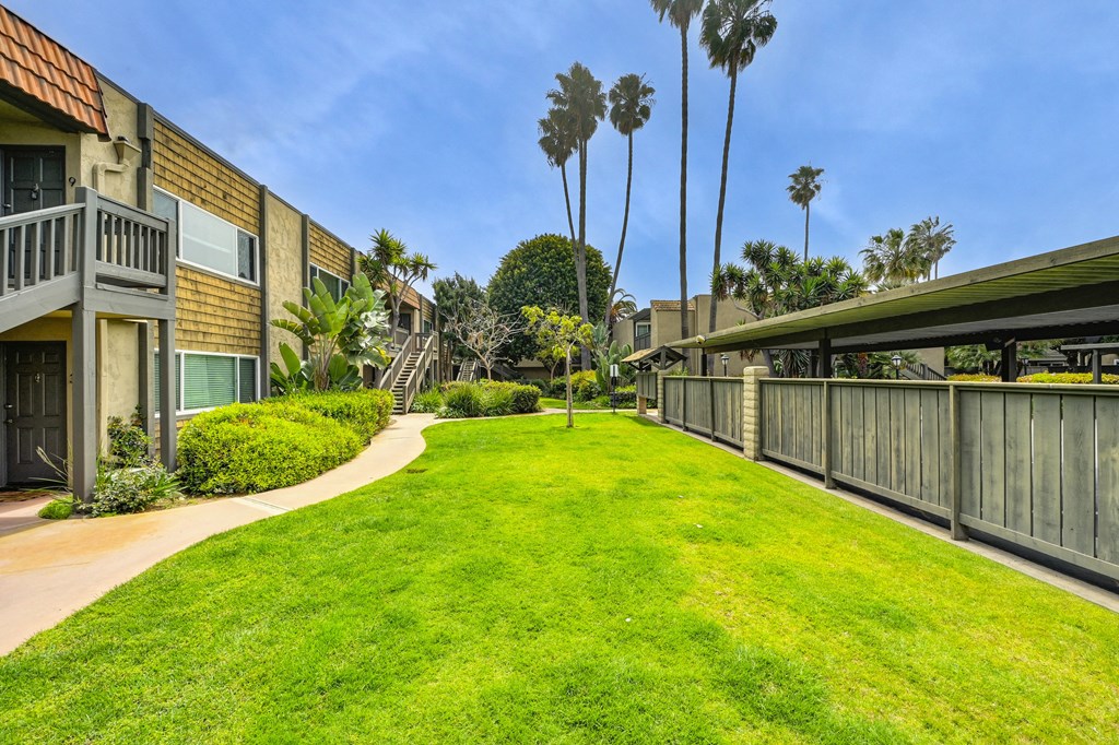 a lush green lawn in front of a building with palm trees