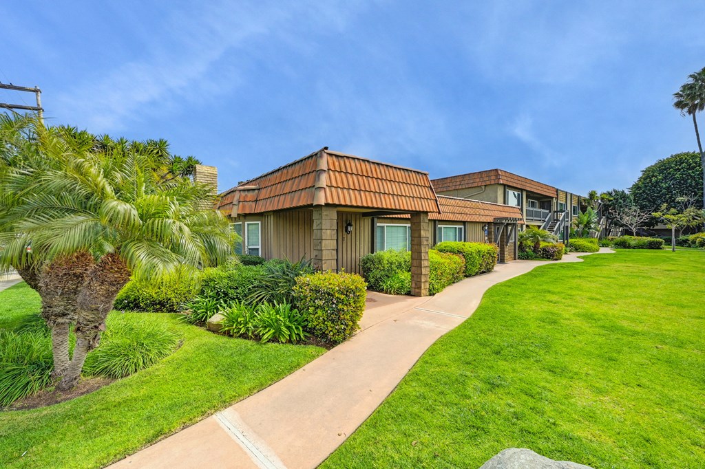 a house with a sidewalk and palm trees in front of it