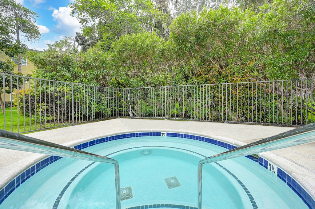 the pool is next to a fence and a yard with trees