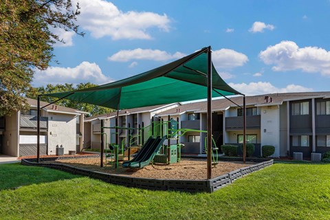 A playground with a green slide and a green canopy.