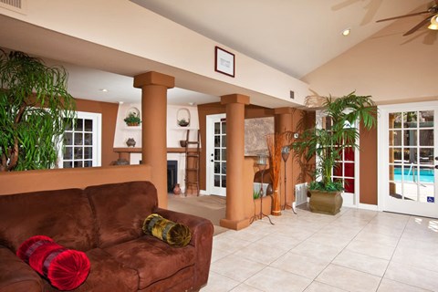 A living room with a brown couch and a pool in the background.