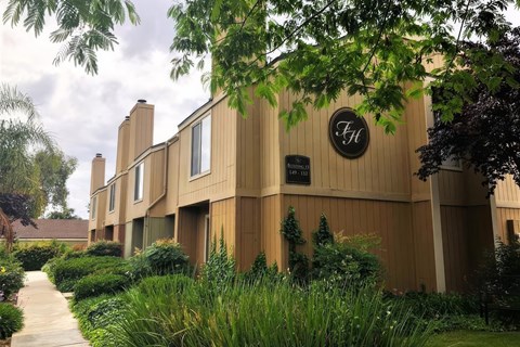 The exterior of Fox Hollow's Apartment Building with a walkway lined with grass and bushes.