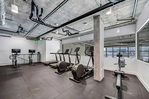 A gym with a variety of equipment including treadmills, weights, and exercise bikes.