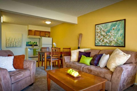 A living room with a couch, chairs, and a painting on the wall.