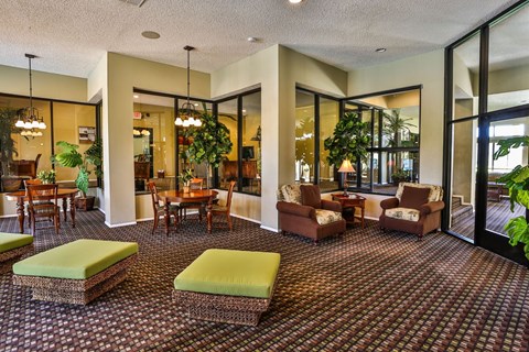Community clubhouse with armchairs, tables and chairs, and cushioned stools.