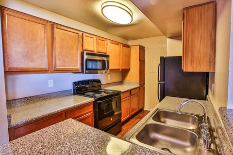 A kitchen with wooden cabinets and a granite counter top.