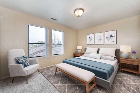 A bedroom carpet, off-white walls, and 2 windows. The room is staged with a bed, chair, a rug, and nightstand.