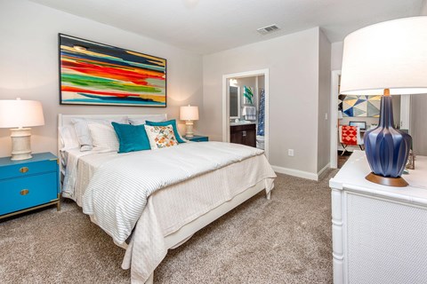 A bedroom with a large bed and a colorful painting on the wall.