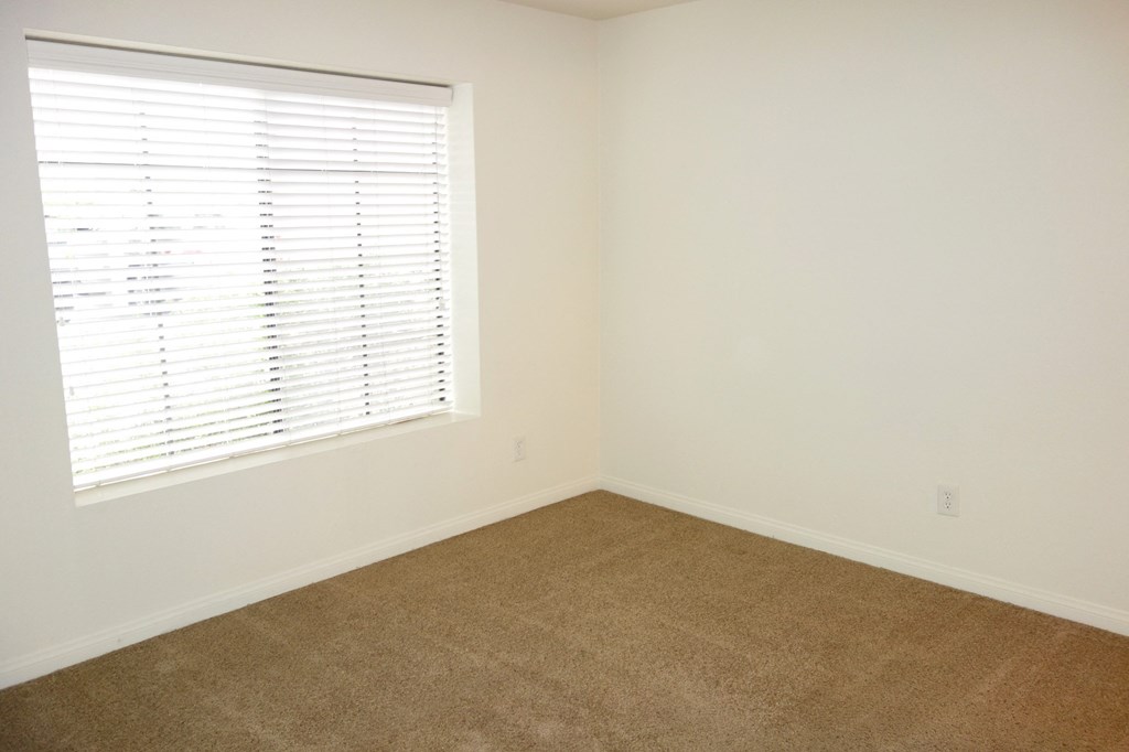a bedroom with white walls and a window with a blind