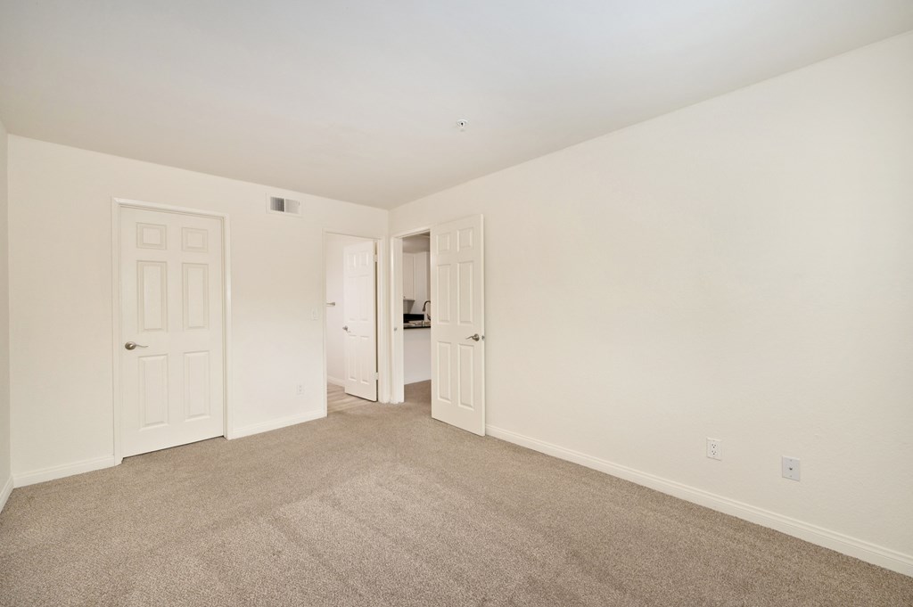 a bedroom with white walls and carpet and white doors