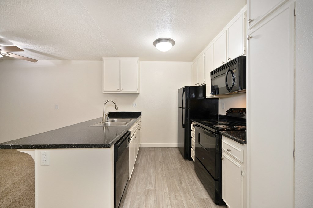 an apartment kitchen with black appliances and white cabinets