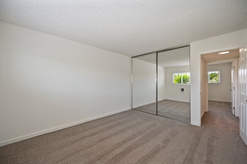 an empty living room with a large mirror and carpeting