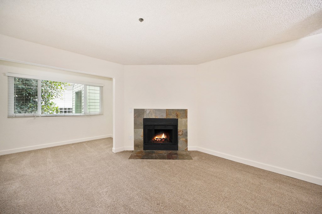 an empty living room with a fireplace and a window
